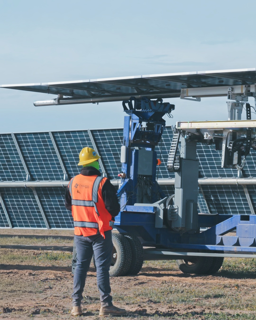 A worker stands beside installation equipment at the solar site.